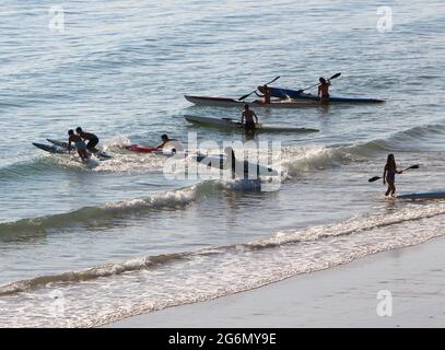 Jeunes avec planches de surf et skis de surf entrant dans l'océan lors d'un matin ensoleillé de printemps Sardinero Santander Cantabria Espagne Banque D'Images