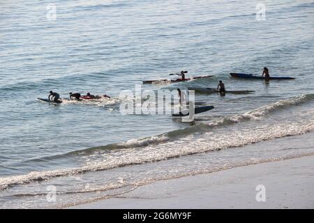 Jeunes avec planches de surf et skis de surf entrant dans l'océan lors d'un matin ensoleillé de printemps Sardinero Santander Cantabria Espagne Banque D'Images