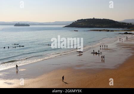 Jeunes avec planches de surf et skis de surf entrant dans l'océan lors d'un matin ensoleillé de printemps Sardinero Santander Cantabria Espagne Banque D'Images