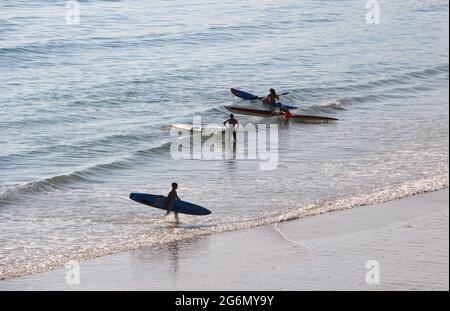 Jeunes avec planches de surf et skis de surf entrant dans l'océan lors d'un matin ensoleillé de printemps Sardinero Santander Cantabria Espagne Banque D'Images