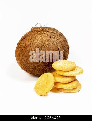 Composition verticale avec cookies de noix de coco biologiques isolés faits maison, avec une noix de coco entière sur un fond blanc. Pâtisseries sucrées à la farine de noix de coco Banque D'Images