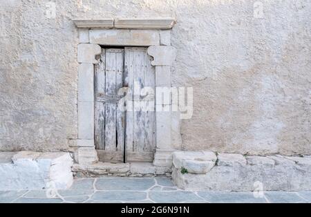 Grèce, Cyclades. Île de Folegandros. Porte en bois avec cadre en marbre, ancienne église sur la place de la ville de Chora. Chapelle traditionnelle des Cyclades, blanchie à la chaux Banque D'Images