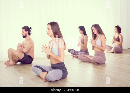 Groupe de jeunes femmes sportives attirantes dans le studio de yoga, la pratique de cours de yoga avec instructeur, l'étirement et la détente pendant l'entraînement . Actif sain Banque D'Images