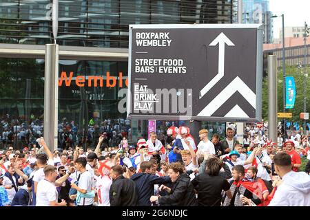 Londres, Royaume-Uni. 07e juillet 2021. Les fans de l'Angleterre chantent et se dantent sous le panneau Boxpark Wembley à l'extérieur du sol. Scenes Ahead off the UEFA Euro 2020 Tournament semi final match, England v Denmark, Wembley Stadium, Londres le mercredi 7 juillet 2021. photo par Steffan Bowen/Andrew Orchard sports Photography/Alay Live News crédit: Andrew Orchard sports Photography/Alay Live News Banque D'Images