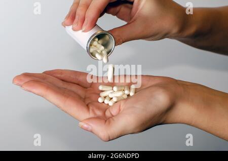 Des pilules médicinales sont déversées de la bouteille de pilule sur le bras. Probiotiques, vitamines, comprimés. Concept de médecine isolé sur fond blanc. Guérir votre Banque D'Images