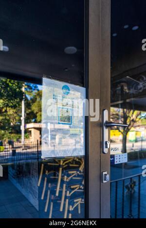 Réflexions dans les fenêtres de bar fermé avec QR checkin signe, à Balmain, Sydney Australie pendant le confinement pandémique Banque D'Images