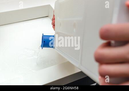 Réservoir de condensats du sécheur, une femme purge l'eau accumulée après avoir séché les vêtements dans le sécheur Banque D'Images