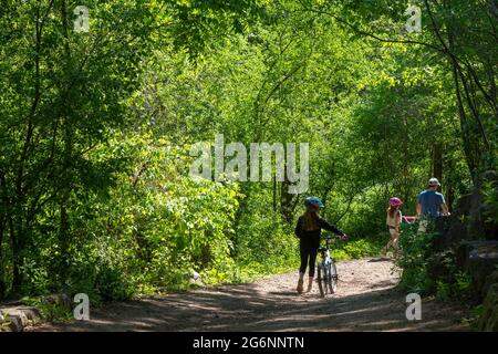 Jeune famille sur une promenade en vélo sur une descente abrupte dans la forêt Banque D'Images