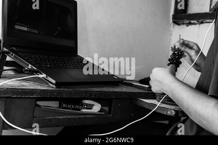 Vieux bureau avec un ordinateur portable noir, une boîte de cartes jack noires en dessous, et il y a quelqu'un assis devant l'ordinateur portable ayant grapefrui Banque D'Images