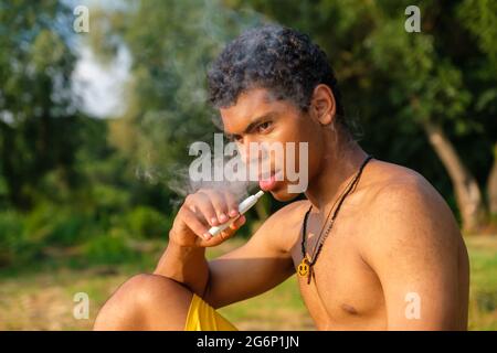 Un jeune homme afro-américain vaporisant de l'e-cigarette à l'aide d'e-liquide Banque D'Images