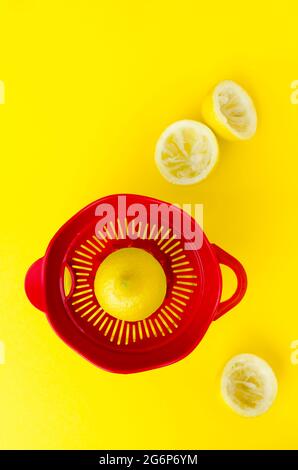 Presse-agrumes rouge avec citrons sur fond jaune Banque D'Images