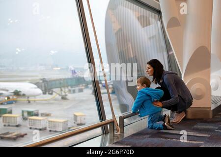 Une mère et un fils regardant les avions par la fenêtre de l'aéroport Banque D'Images