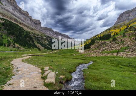 Sentier de randonnée avec petite crique de montagne sous les nuages de pluie dans le parc national espagnol Ordesa y Monte Perdido, Pyrénées, Espagne Banque D'Images