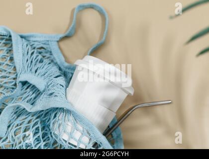 Sac en coton bleu réutilisable et tasse à café sur fond beige. Sac de shopping écologique. Gros plan. Concept d'épicerie zéro déchet. Banque D'Images