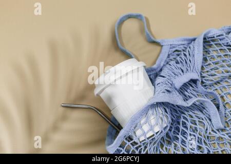 Sac en coton bleu réutilisable et tasse à café sur fond beige. Sac de shopping écologique. Gros plan. Concept d'épicerie zéro déchet. Banque D'Images