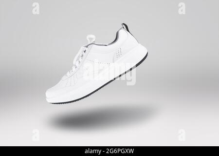 Nouvelle sneaker blanche flottante sur fond gris. Gros plan sur les chaussures de sport. Style Street Banque D'Images