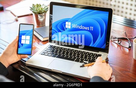 Grèce Athènes, juillet 8 2021. Homme avec un ordinateur portable et un smartphone, Windows 11 nouveau système d'exploitation Microsoft sur les écrans, bureau backgro Banque D'Images