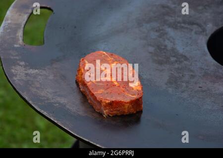 plaque de cuisson sur feu de bois chaud avec steak de porc marinade en gros plan Banque D'Images