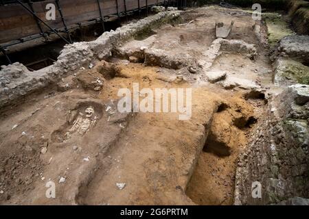 Une vue de ce que l'on croit être les restes d'un moine du XIIe siècle sur le North Green à l'abbaye de Westminster, Londres, pendant un aperçu avant que le site archéologique de creusage s'ouvre au public plus tard ce mois-ci dans le cadre de la visite Hidden Highlights. Le squelette, partiellement couvert dans le sol, a été déterré lors des fouilles de la Grande Sacristie, où les moines ont conservé des vêtements, des linges d'autel, et d'autres objets sacrés utilisés dans la masse. Date de la photo: Mercredi 7 juillet 2021. Banque D'Images