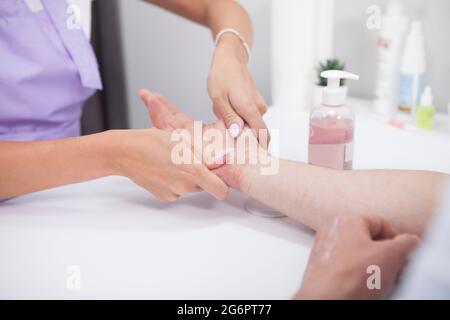 Coupe courte d'un homme méconnaissable dont les mains sont massées par un manucuriste Banque D'Images