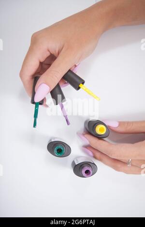 Vue verticale du dessus des mains de femmes tenant des flacons de gel pour ongles avec vernis à ongles coloré Banque D'Images