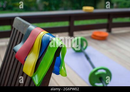 Les bandes élastiques se rapprochent. Équipement de formation à la maison sur la terrasse de la cour. Fitness à la maison. Concept de santé, de formation et de style de vie. Banque D'Images