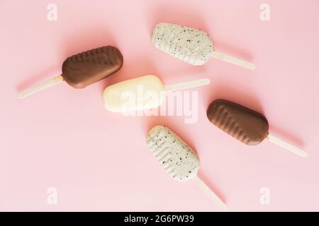 Plat de la différence des pop-glaces au chocolat sur fond pastel. Banque D'Images