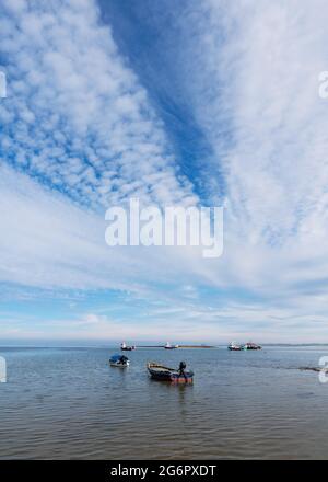 Vue panoramique de petits bateaux de pêche ancrés dans la mer avec des nuages, Holy Island, Northumberland, Royaume-Uni Banque D'Images