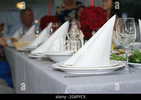 Les serviettes blanches se tiennent dans un triangle dans des assiettes propres à côté des verres sur une table de fête magnifiquement servie Banque D'Images