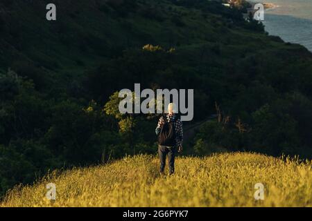 Homme voyageur, avec un sac à dos, regarde les montagnes et la forêt étonnantes, jeune homme sur une promenade de campagne, un jour d'été, randonnée dans la campagne, tr Banque D'Images