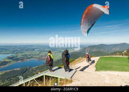 Schwangau, Allemagne - 11 octobre 2017: Parapentes commençant sur le Tegelberg au point de saut avec d'autres athlètes debout à côté d'eux. Banque D'Images