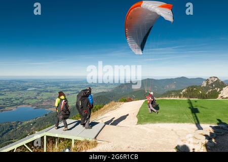 Schwangau, Allemagne - 11 octobre 2017: Parapentes commençant sur le Tegelberg au point de saut avec d'autres athlètes debout à côté d'eux. Banque D'Images