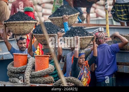 Une chaîne humaine de porteurs transporte du charbon, du sable et du gravier depuis les barges amarrées à la station d'atterrissage d'Aminbazar, sur le fleuve Buriganga, à l'extérieur de Dhaka. Le Bangladesh est diplômé de la catégorie des PMA (pays les moins avancés), grâce en grande partie au travail extrêmement difficile de la main-d'œuvre manuelle bon marché. Un porteur fait entre 80 et 140 USD par mois, selon les sites paylab.com et averagesalarysurvey.com Banque D'Images