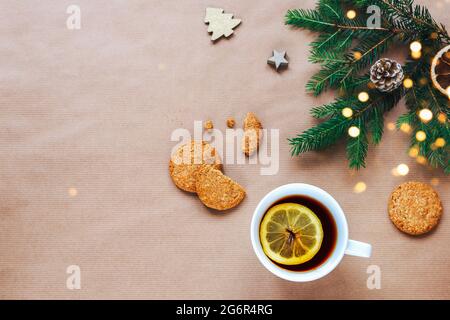 Arrière-plan des fêtes de Noël et du nouvel an. Branches d'arbre de Noël, tasse de thé et biscuits sur fond beige. Vue de dessus, plat, espace de copie Banque D'Images