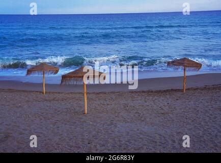 Trois parasols sur une plage solitaire. Banque D'Images