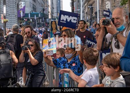 Des spectateurs avec des panneaux remerciant les travailleurs essentiels assistent à la parade des ticker « Hometown Heroes » à New York. Les travailleurs de la santé, les premiers intervenants et les travailleurs essentiels sont honorés dans le Canyon of Heroes de Manhattan pour leur service durant la pandémie de Covid-19. Banque D'Images