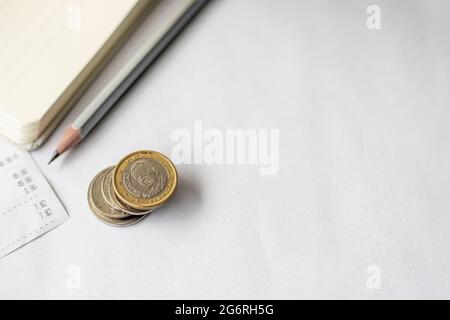 Carnet financier vierge avec un reçu à côté D'UN crayon et des pièces en euros empilées. Bloc-notes de budget vide avec UN tas de stylo et de monnaie. Banque D'Images