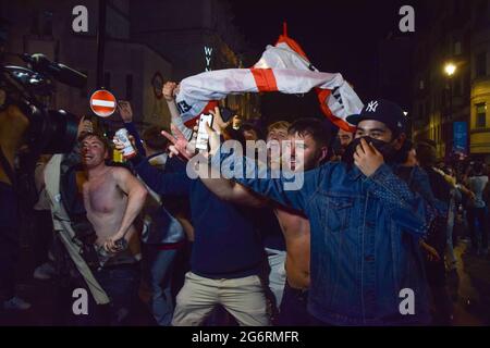 Londres, Royaume-Uni. 07e juillet 2021. Les fans de football jubilant arborent un drapeau anglais et applaudissent devant une caméra de télévision à Leicester Square après la victoire de l'Angleterre sur le Danemark lors de la demi-finale de l'Euro 2020.des milliers de supporters jubilants se sont rassemblés dans le centre de Londres pour célébrer la place de l'Angleterre dans la finale du championnat de football Euro 2020. (Photo de Vuk Valcic/SOPA Images/Sipa USA) crédit: SIPA USA/Alay Live News Banque D'Images