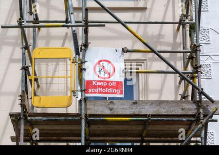 Échafaudage sur le côté d'un bâtiment avec un panneau qui lit tenir à l'extérieur de l'échafaudage Banque D'Images