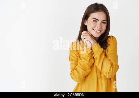 Portrait de petite amie romantique recevant un cadeau, souriant et regardant heureux à l'appareil photo, debout reconnaissant sur fond blanc Banque D'Images