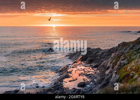 Un coucher de soleil spectaculaire sur les rochers des piscines sur la côte de Newquay dans les Cornouailles. Banque D'Images