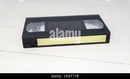 Vue rapprochée d'une ancienne cassette VHS avec une étiquette vierge sur une surface en bois blanc Banque D'Images