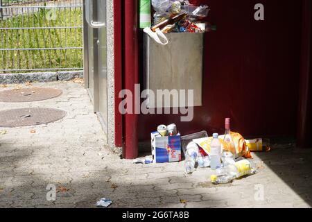 La nourriture est débarée dans et autour de la poubelle publique de l'arrêt de bus. Il y a des canettes de boissons non alcoolisées vides, des emballages de collations. Banque D'Images