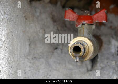 Bavette de tuyau d'extérieur ou borne d'eau installée dans le mur. Il fuit légèrement et il y a une goutte d'eau sur le point de tomber. L'espace de copie est à gauche. Banque D'Images