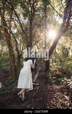 Jeune couple asiatique tenant des mains de randonnée dans la forêt avec la lumière du soleil dans le parc national Banque D'Images