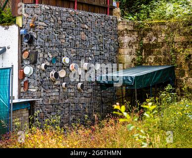 Gabion dans un jardin avec des pots de cuisson jetés qui y sont suspendus à Sonneberg, en Allemagne Banque D'Images