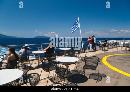 Poros, île de Céphalonie, Grèce - juillet, 17 2019: Passagers du bateau de croisière se détendant à l'arrière-pont ouvert et regardant le paysage de montagne de Banque D'Images