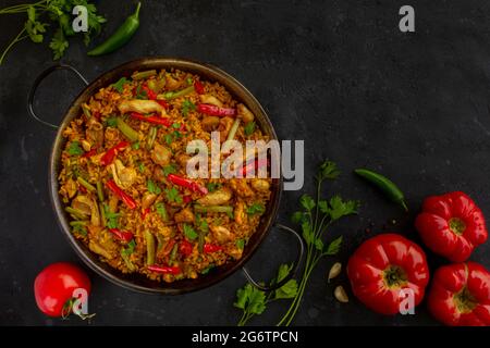 riz à la paella espagnole avec poulet sur fond sombre Banque D'Images