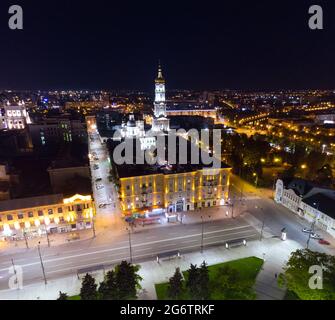 Vue aérienne du centre-ville de Kharkiv, Ukraine. Vue latérale depuis Maidan Konstytutsii. Cathédrale de Dormition illuminée par les lumières du soir. Banque D'Images