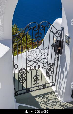 Maison de l'île grecque, architecture traditionnelle sur l'île de Santorini. Vue sur la mer depuis une porte en fer noir ; entrée à la maison. Banque D'Images